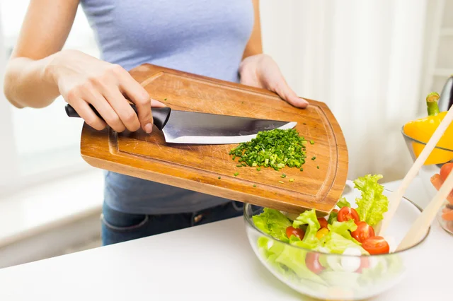 close up of woman with chopped onion cooking salad